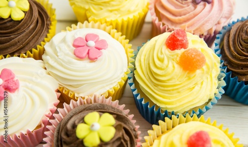 Фотография Flat design showing cupcakes on wood surface with liners, buttercream, fondant f