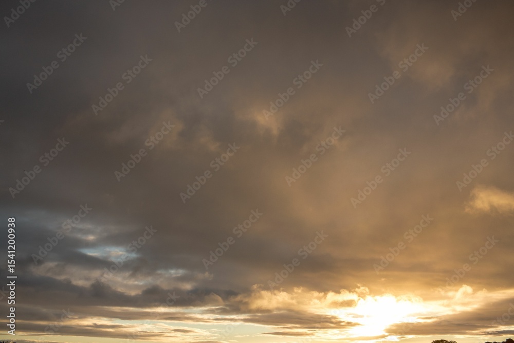 Obraz premium Expansive cloud layers are drifting across sunset sky in flat design with glowing sun rays