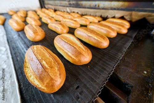 Freshly baked bread rolls emerge from the bakery oven in a warm and inviting atmosphere