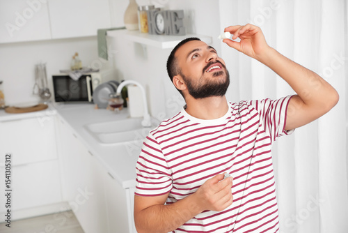Young man applying eye drop...