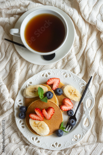 Light breakfast, pancakes with fruits and berries on the table.