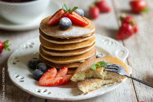 Light breakfast, pancakes with fruits and berries on the table.