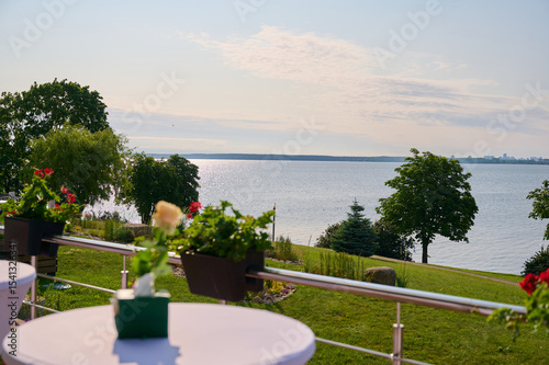 scenic lakeside terrace view with flower pots and tables overlooking calm waters, perfect for relaxation, gatherings, or events. ideal outdoor setting for nature enthusiasts. photo
