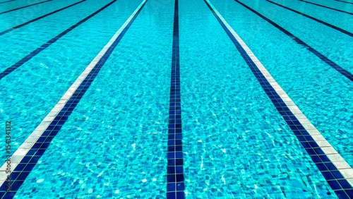 Bright, clear swimming pool with marked lanes under sunlight showcasing vibrant blue water