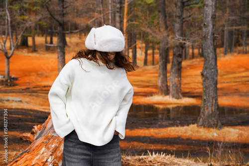 Young female walks on ground with yellow-orange dry fall leaves during autumn season in park or forest. Girl traveler walking in outdoor nature. Healthy lifestyle on leisure activity