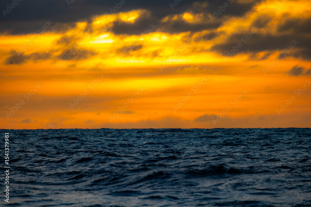 Fototapeta premium A breathtaking and stunning view of the vast ocean at sunset, showcasing vibrant, rich hues of orange and blue