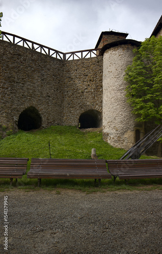 Wooden benches in the castle courtyard. Stone castle in the background. Wooden benches in the courtyard.