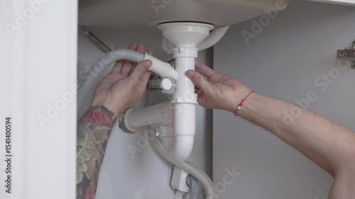 Close Up of Plumber Repairing Leaking Sink Drain in Kitchen photo