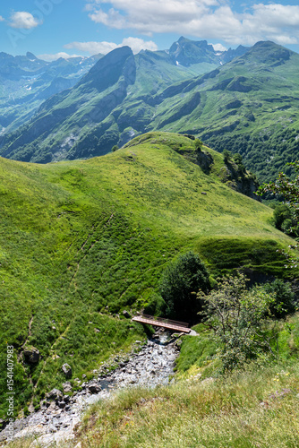 Mountain range with a green hillside and a bridge over a river