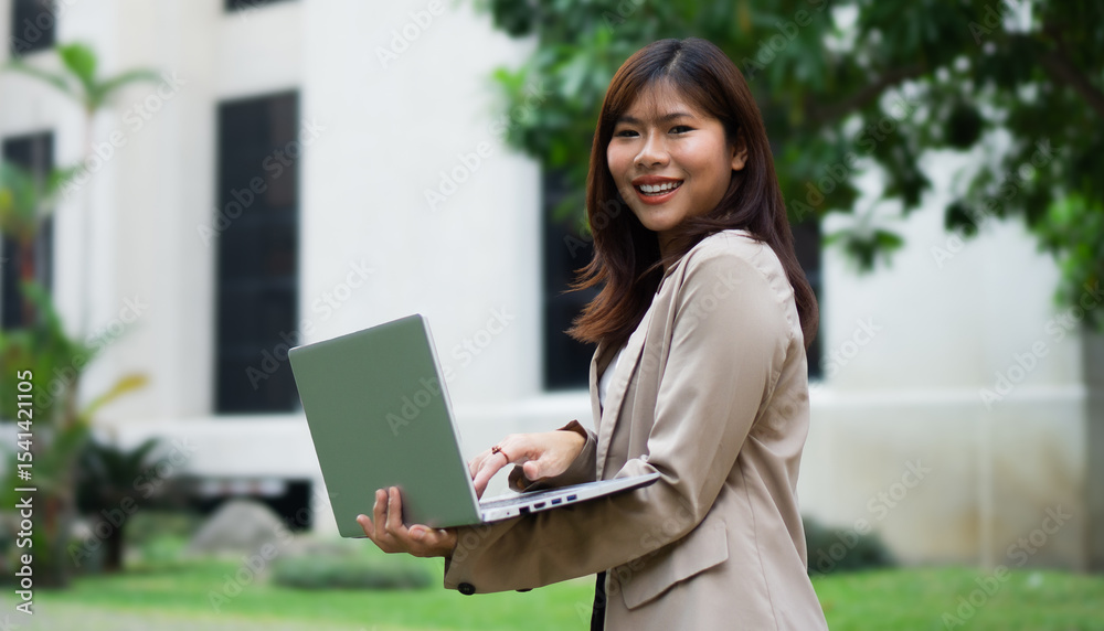 Portrait happy Asian businesswoman working on laptop in city. Portrait happy Asian businesswoman working on laptop in city.