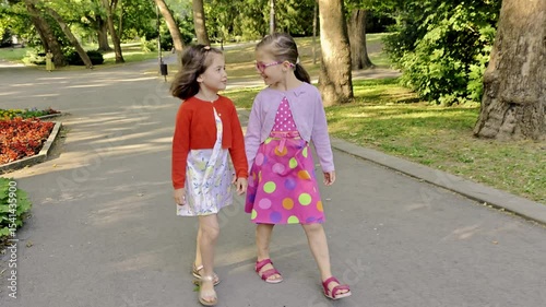 Happy children. Two girls walking in the park. Two little sisters walking together, talking. Best friends