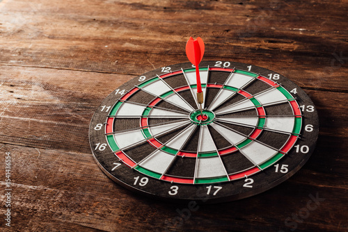 Dartboard with Red Dart on Wooden Table in a Game Setting