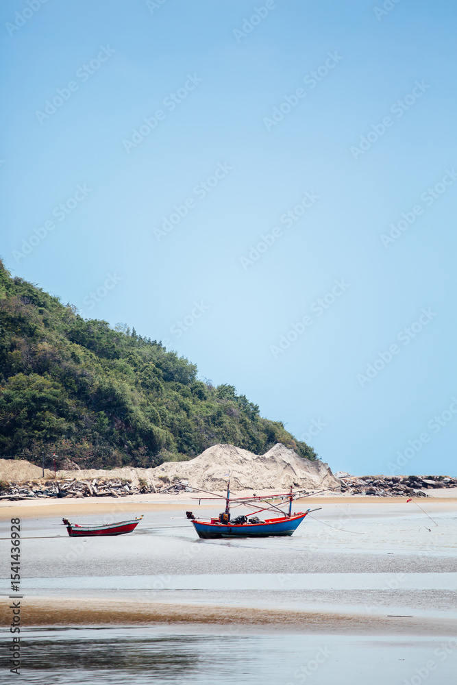 Fototapeta premium Fishing boats on serene beach under clear blue sky landscape