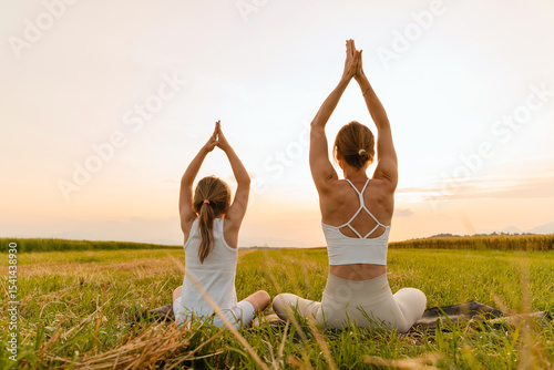 Mother and daughter practicing yoga poses in nature.
