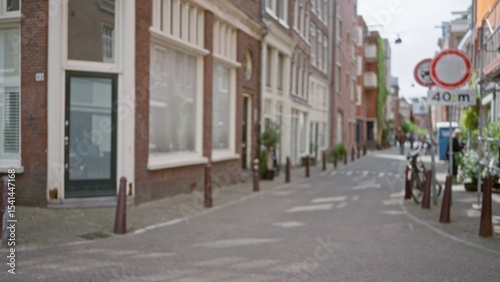 European street scene with blurred buildings and defocused pedestrians, showcasing urban charm, cobblestone paths, and a distinct bokeh effect in natural daylight.