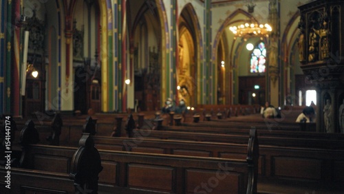 Принти на полотні Blurred church interior with defocused pews and few people in the background, showcasing ornate arches and stained glass windows in a serene, spiritual setting