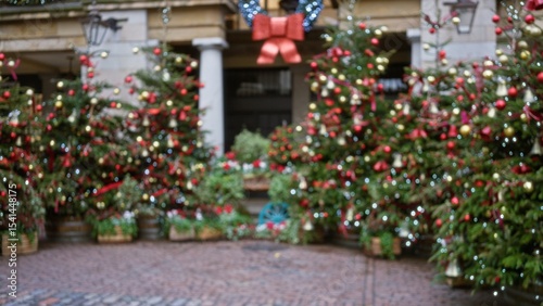 Defocused view of festive christmas decorations in covent garden, london, featuring blurred winter trees adorned with lights and ornaments in a charming, bokeh-filled street setting.