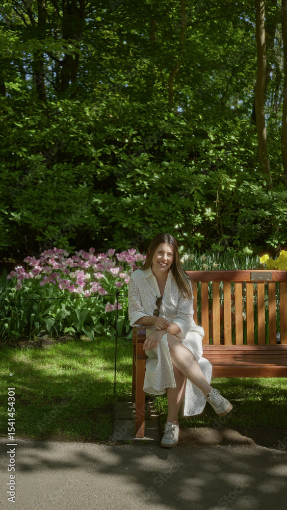 Fototapeta premium Woman sitting on a bench in a tulip garden in lisse, netherlands, surrounded by vibrant flowers and lush greenery, enjoying a sunny day.