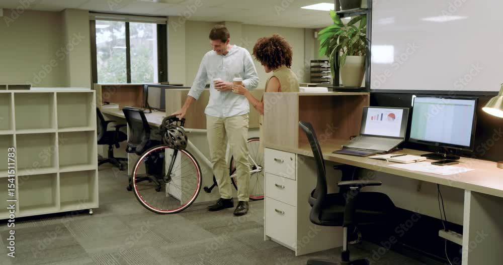 Diverse coworkers catching up while man entering office wheeling bicycle and offering coffee sip