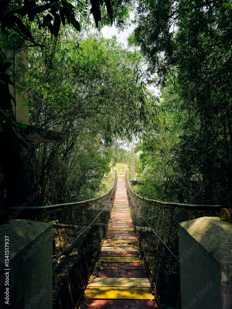 Fototapeta premium Colorful Wooden Suspension Bridge Through Forest PathColorful Wooden Suspension Bridge Through Forest Path