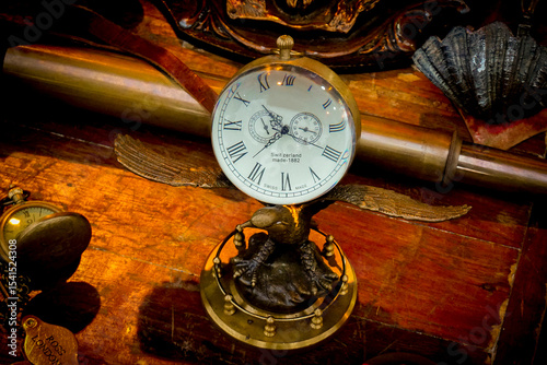Antique table clock. Time passes by...Vintage clocks and pink hourglass tell stories of the past on old wooden floors. Every second that passes has its own value.