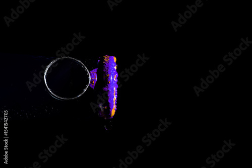 Side view of a soda can lid with water droplets, dark background, close-up macro shot.


