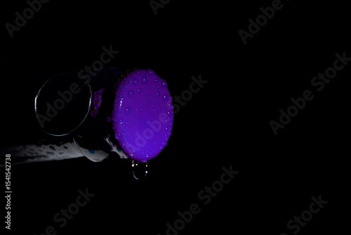 Macro photo of a green soda can lid with water droplets, dark background, high contrast close-up.


