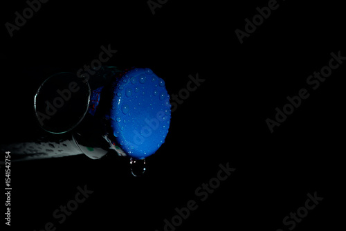 Macro photo of a green soda can lid with water droplets, dark background, high contrast close-up.

