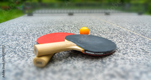 Rackets for table tennis in park close up. Red black ping pong table tennis paddles and yellow ball