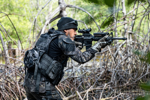 military men in combat gear patrol in the middle of tropical jungle.