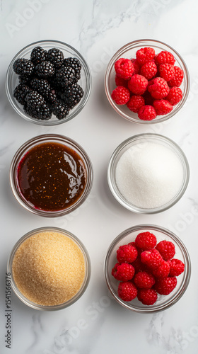 Six glass bowls arranged in two rows feature blackberries, raspberries, brown sugar, white sugar, and a dark syrup, all set against a marble background.