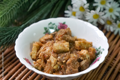 A bowl of Sambal Goreng Pengantin, a rich, traditional Malay dish made from a combination of beef liver, lung, trimmings, spleen, prawns, tofu, and tempe in coconut gravy, perfect for festive meals.
