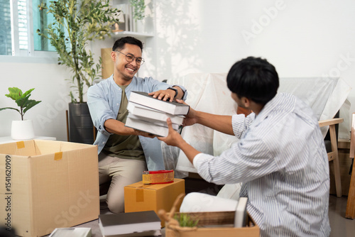 Gay couple collaborating on unpacking boxes in their cozy living room photo