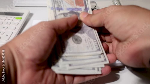 A student reveals a stack of cash prepared for tuition or school costs, with a white envelope marked 