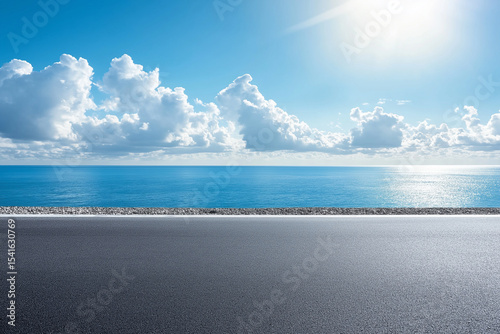 Asphalt road leading to ocean with clear blue sky, great for vacation banners or transportation concepts