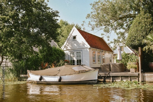 Obraz na plátně Charming lakeside cottage with docked boat.