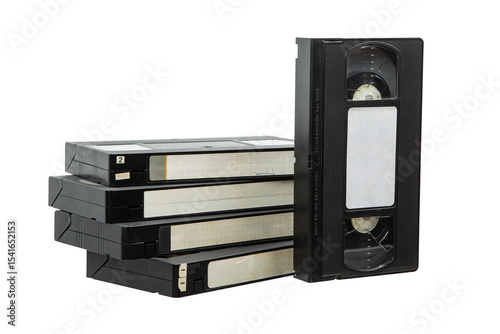Stack of old VHS video tapes with worn labels and one tape standing upright on a white back