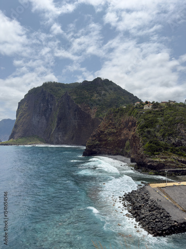 Ocean waves crash against rugged coastline of Madeira, Portugal, creating breathtaking seascape with white surf, sea spray, and jagged stones.