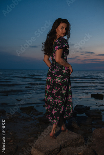 Woman in dress standing near the lake at evening
