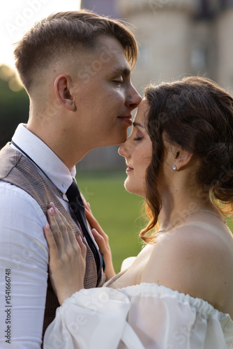 Harmony and romance of the wedding day. The exemplary attitude of the groom to his wife. The groom kisses the forehead of the bride with his eyes closed. The tender touches of the girl to the guy.