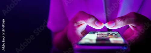 Finger of woman touching scroll page app on mobile phone.In a room with blue and purple neon tones.concept Social media and marketing