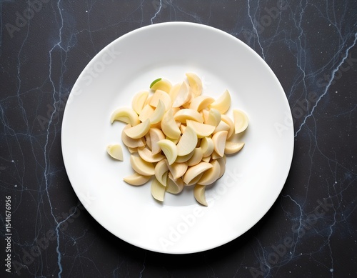 Sliced Garlic Cloves on White Plate Overhead View Food Photography