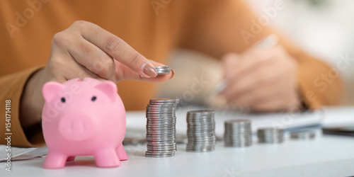 Financial Empowerment. Person saving coins in pink piggy bank for future goals.