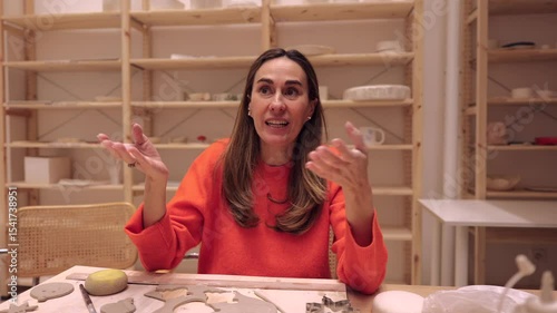 Professional ceramist demonstrating pottery techniques while guiding student during hands on workshop, sharing specialized knowledge through personal artistic instruction