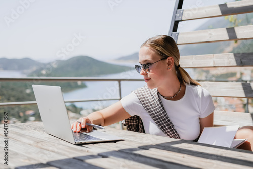 digital nomad woman working remotely from a cozy kitchen during breakfast. Remote work, sustainability, wellness, Gen Z, conscious living, home office and online freelancing