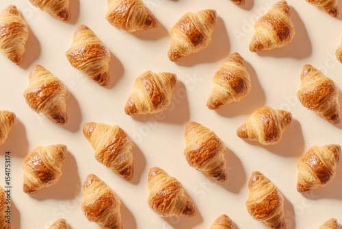 Freshly baked croissants arranged in an inviting pattern on a neutral background showcasing their golden-brown texture