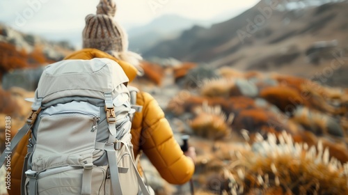 A solo traveler braving the rugged terrain adorned by vibrant fall colors while carrying a backpack and trekking pole showcases the spirit of adventure and exploration.