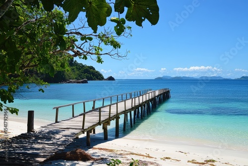 Tranquil wooden pier on pristine beach. Lush foliage frames the scene