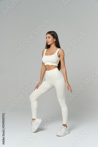 Brunette female model showcases sporty fitness wear in stylish studio setting