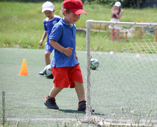 little three-year-old boys plays football at a sports school .